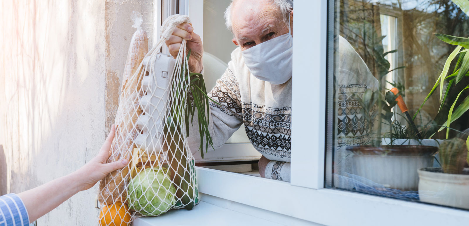 elderly man receiving groceries through window