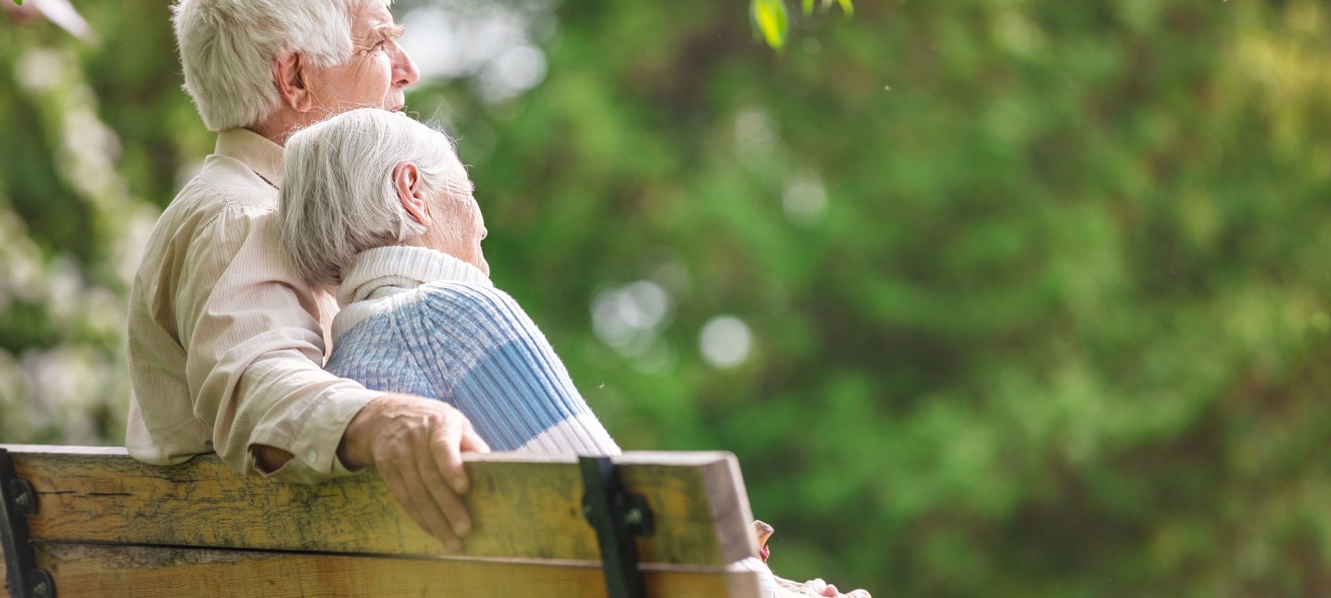 elder couple hugging on a bench