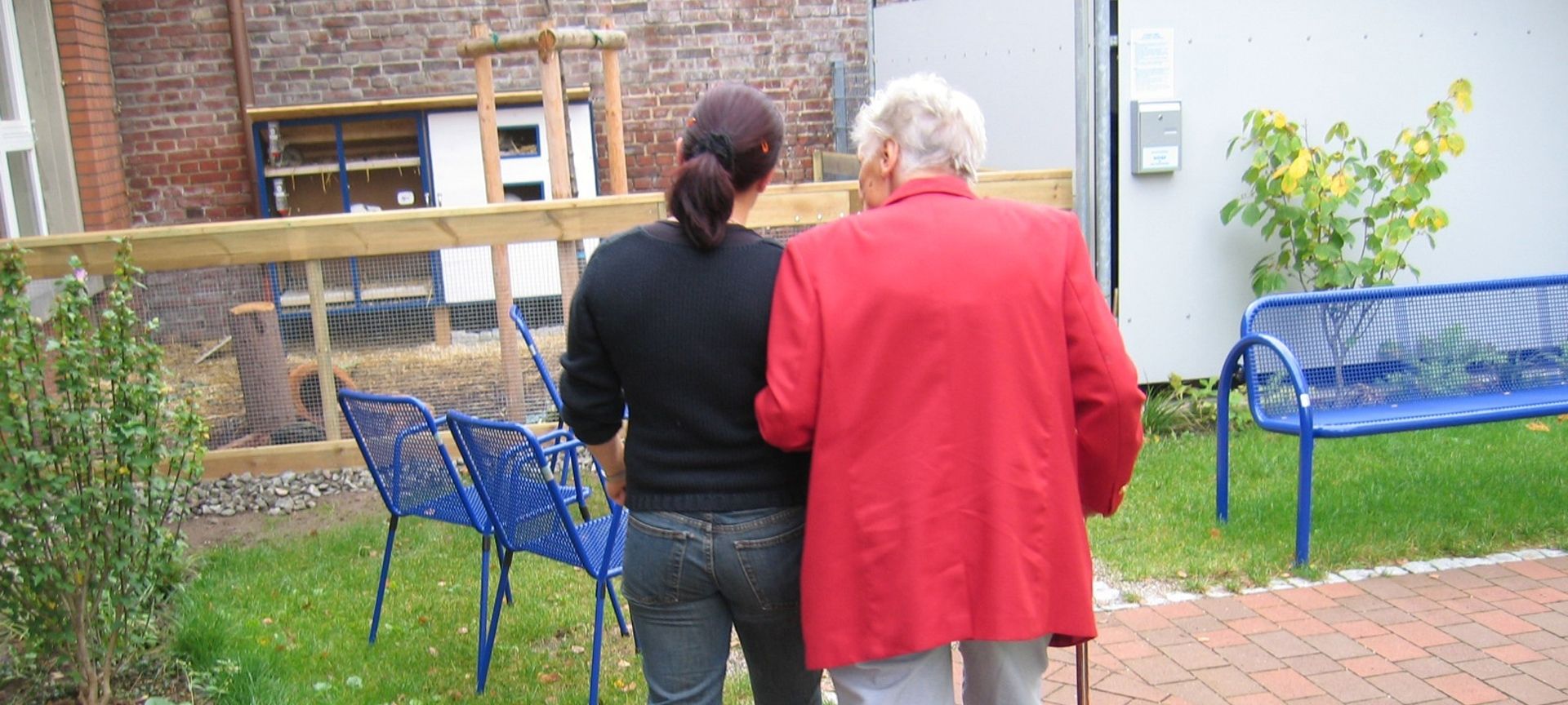 elderly lady being escorted around a garden