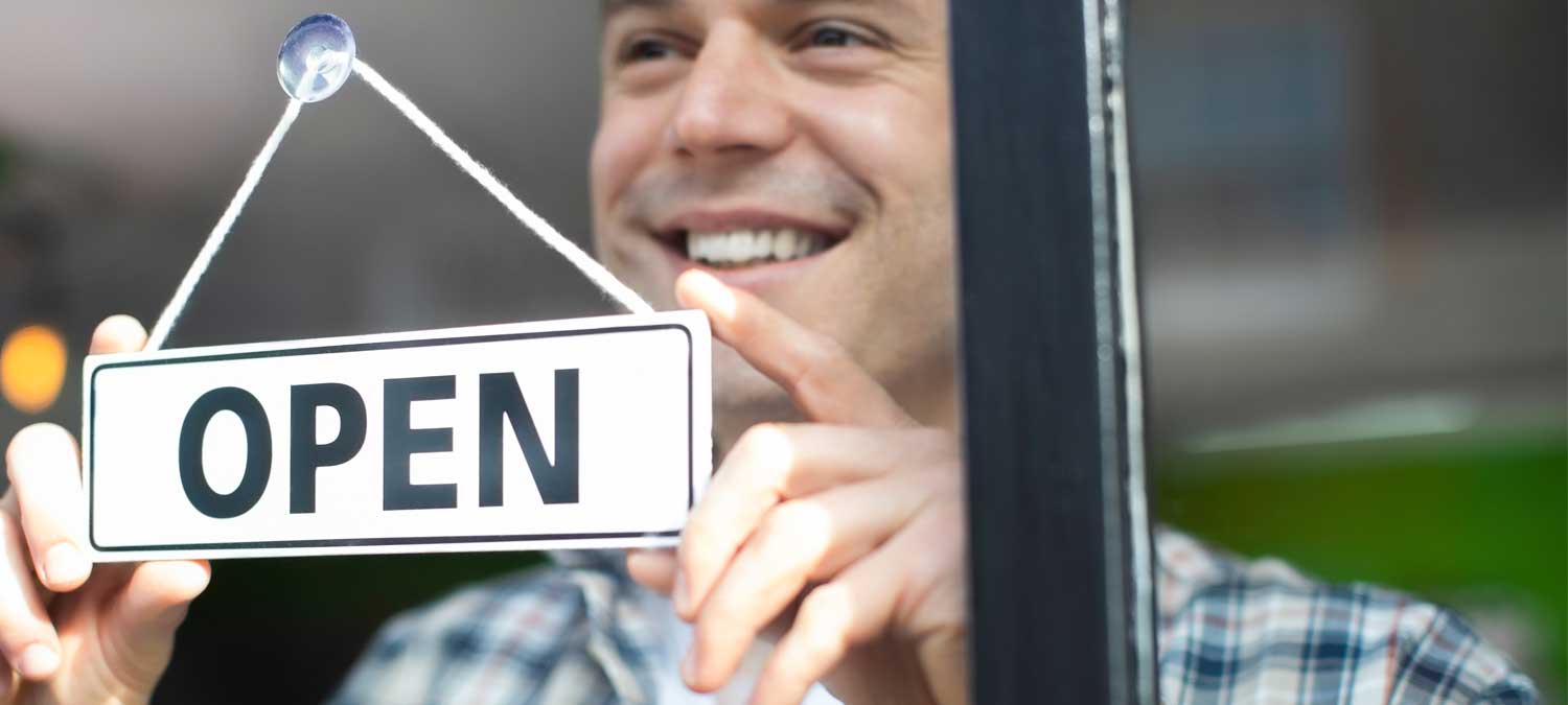 photo of a man putting up an open sign