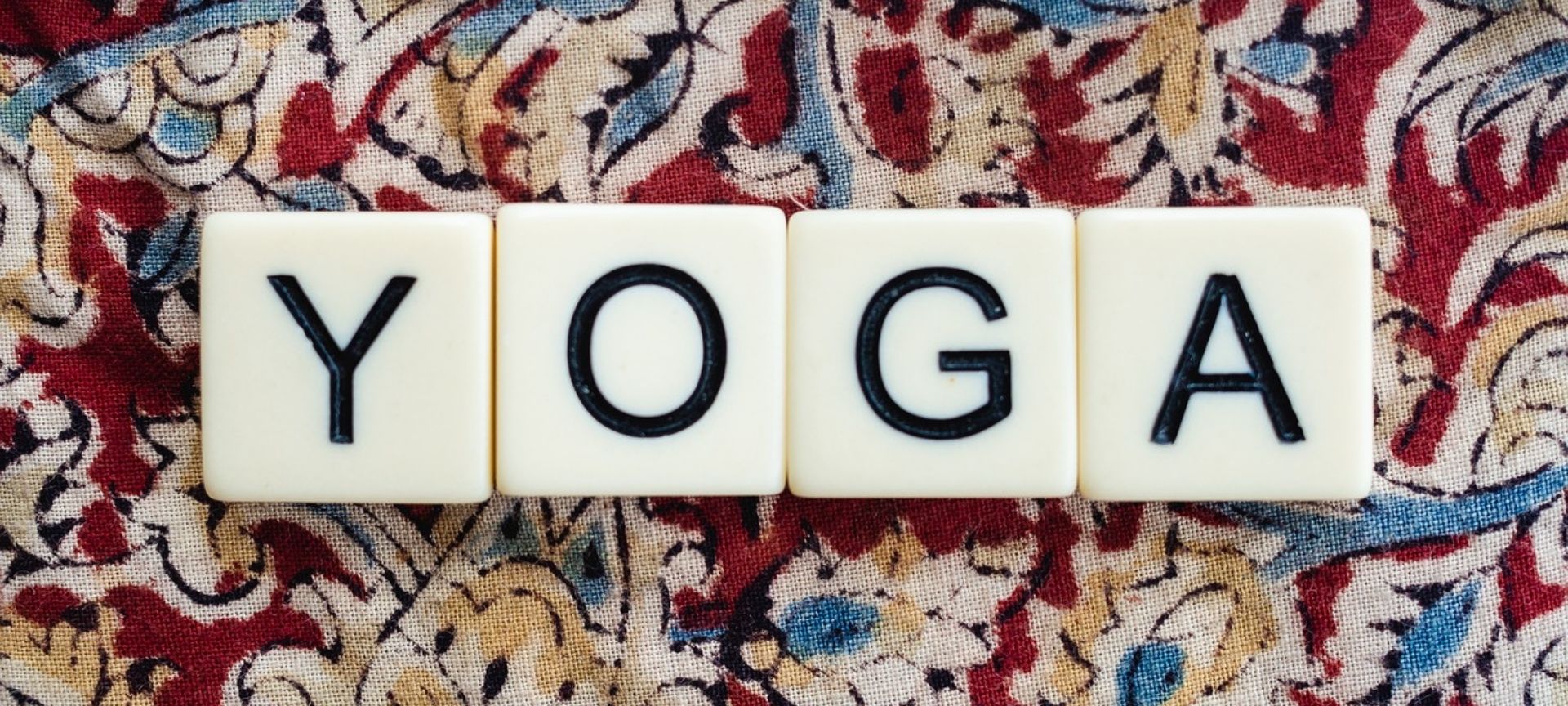 Scrabble squares spelling yoga sitting on a piece of cloth