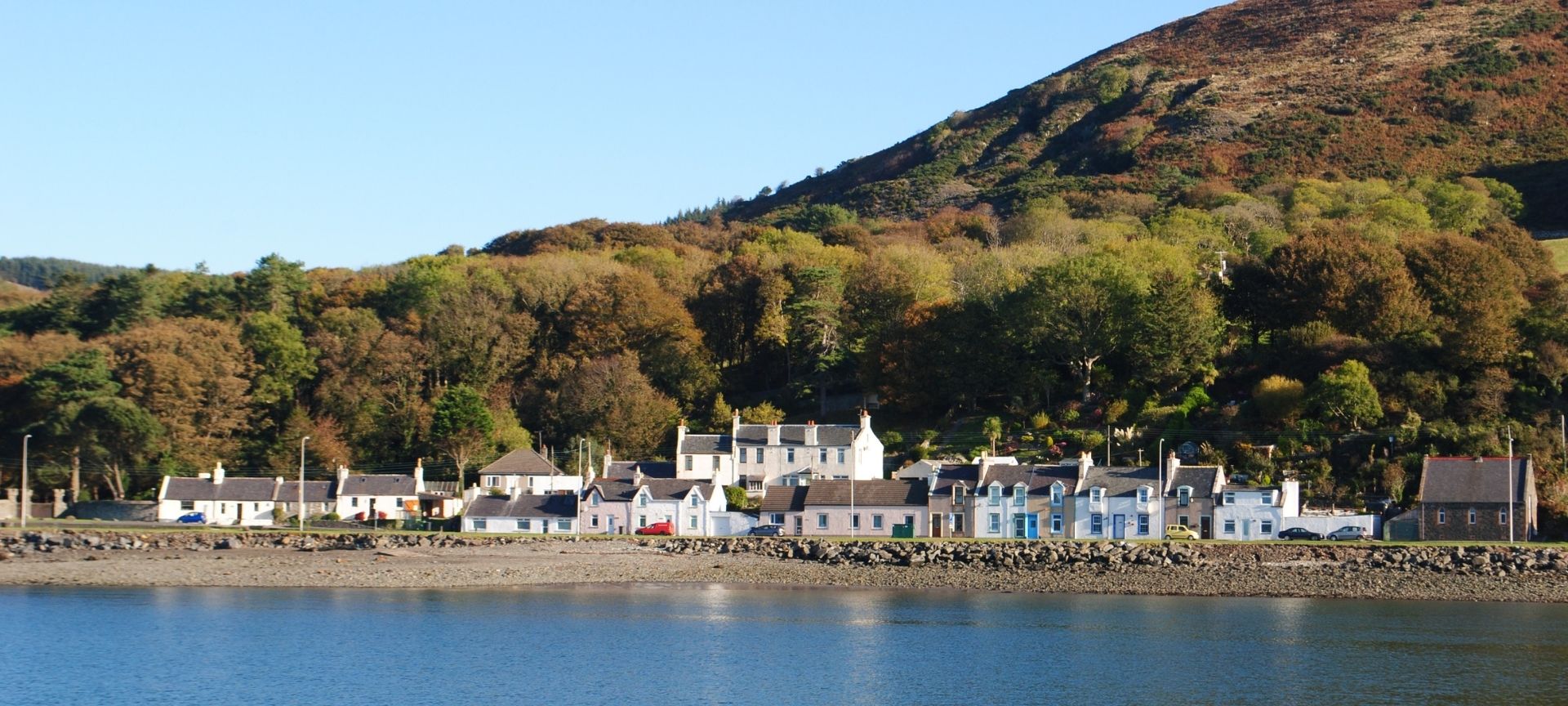 Row of houses with water in front and hills in the background