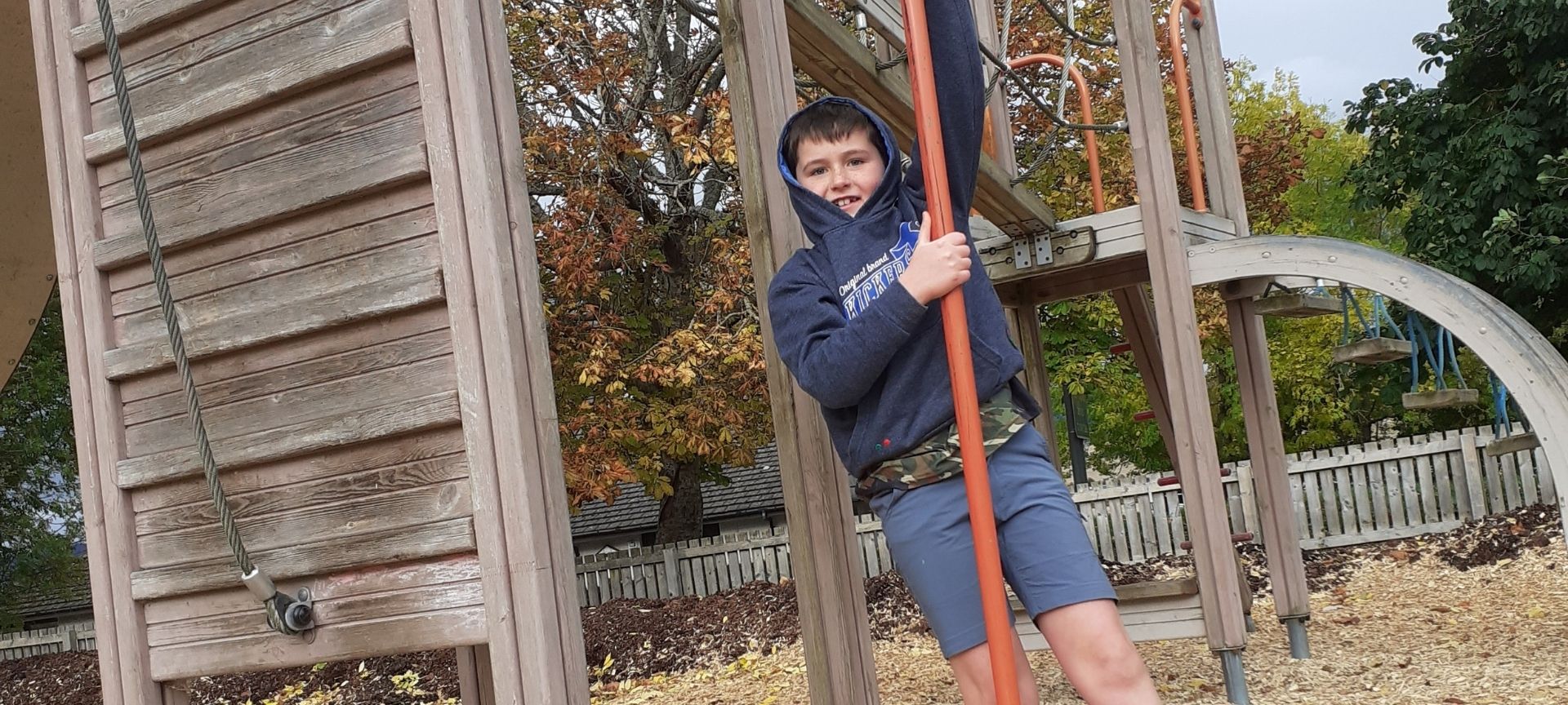 Boy climbing fireman's pole in playground