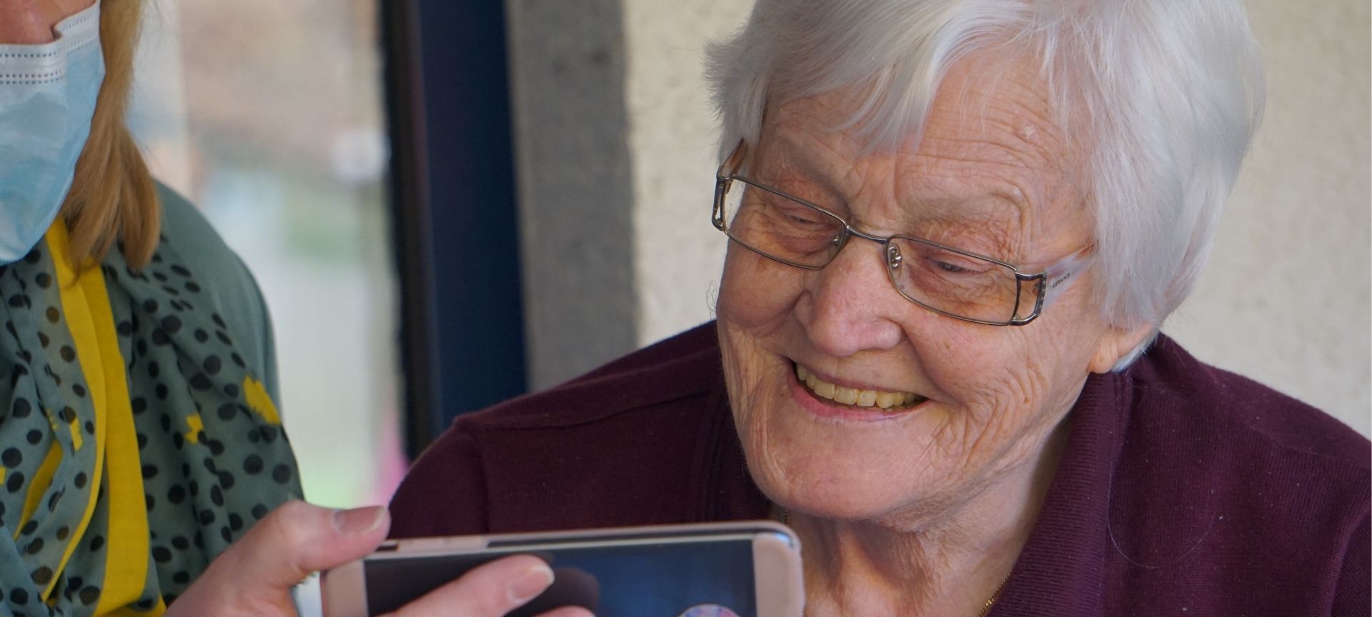 Elderly lady being shown how to use a smartphone