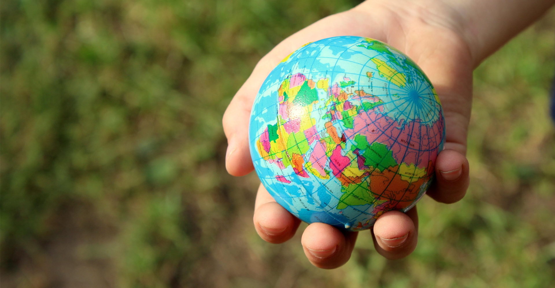 childs hand holding a small planet earth model