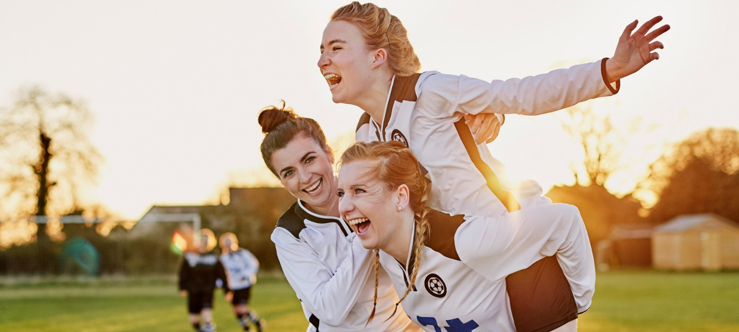 3 girls celebrating while playing football